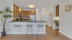 Una cucina moderna con mobili in legno, un frigorifero in acciaio inossidabile, un forno a microonde e una grande isola con sgabelli da bar.
