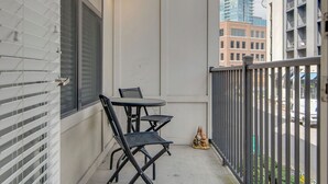Ein Balkon mit Tisch und Stühlen, ein Hydrant und eine Aussicht auf Gebäude sowie einen Baukran.