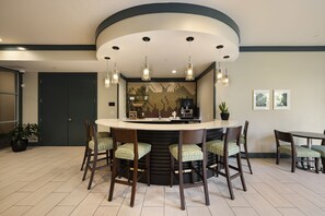 A modern kitchen with a central island, bar stools, pendant lighting, and a tiled backsplash.