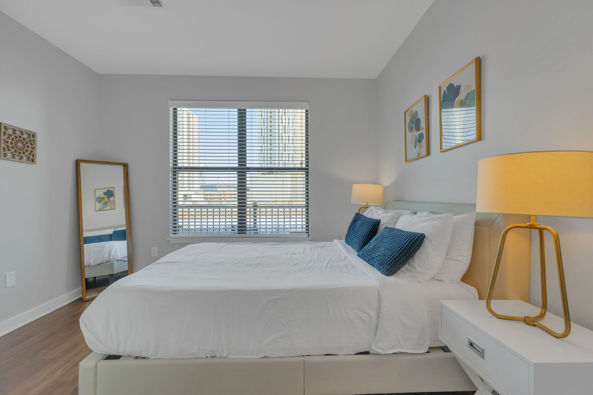 Un dormitorio con cama, mesita de noche, lámpara y ventana con persianas.