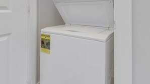 A white washer and dryer unit with a control panel and a yellow sticker on the front.