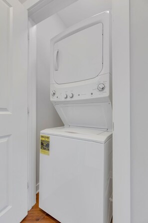 A white washer and dryer unit with a control panel and a yellow sticker on the front.
