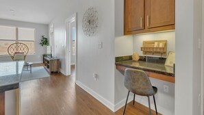 A modern kitchen with wooden cabinets, a granite countertop, and a welcome sign. - Perfect Pad in the Gulch! 2BR & Gym! (Nashville)