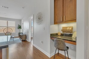 A modern kitchen with wooden cabinets, a granite countertop, and a welcome sign. - Perfect Pad in the Gulch! 2BR & Gym! (Nashville)