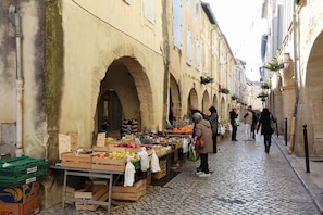 A narrow cobblestone street with a fruit market stall under an archway. - Charming Renovated Apartment Near the Historic Center of Tarascon (Tarascon)