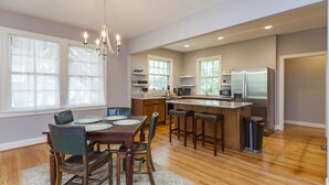 A spacious kitchen with a central island, wooden flooring, and a chandelier. - Charming Hillsboro Home Near Vanderbilt (Nashville)