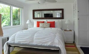 Relax in this serene bedroom with a large bed, bedside tables, and a mirror above, offering a peaceful view of the surrounding greenery.