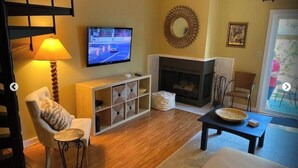 Una sala de estar con chimenea, televisión y escalera.