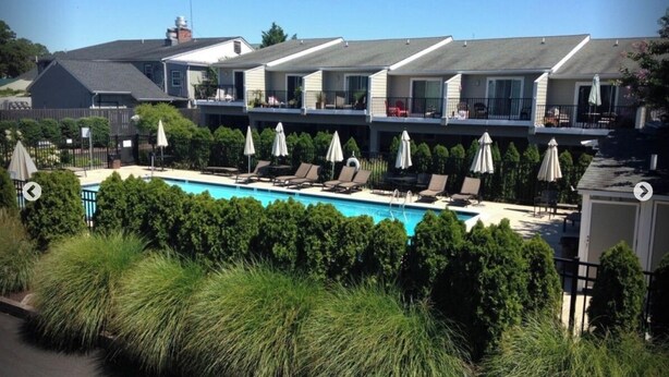 Un hotel con piscina, sillones de descanso y sombrillas.