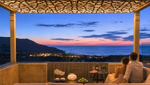 A balcony with a view of the sea and a cityscape at dusk. - Mistral Suite Heated Pool (Chania)