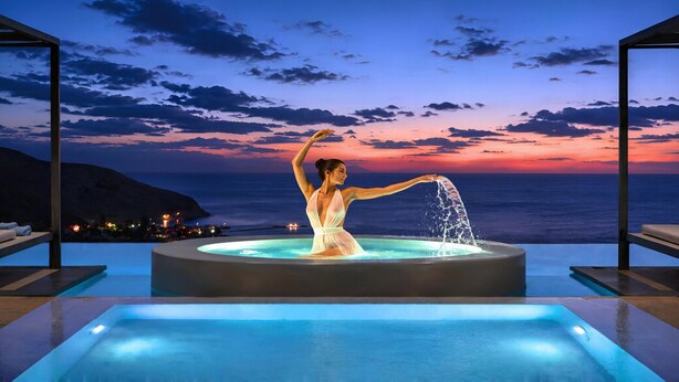 A person in a white dress at a pool with a sunset view. - Mistral Suite Heated Pool (Chania)