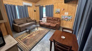 A cozy living room with two sofas, a coffee table, and a dining table with chairs. - Field House on Lake Godstone (Graford)