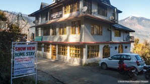 A two-story lodge with a sign indicating it is a home stay under a tourism concept. - Snow view Home Stay (Naggar)