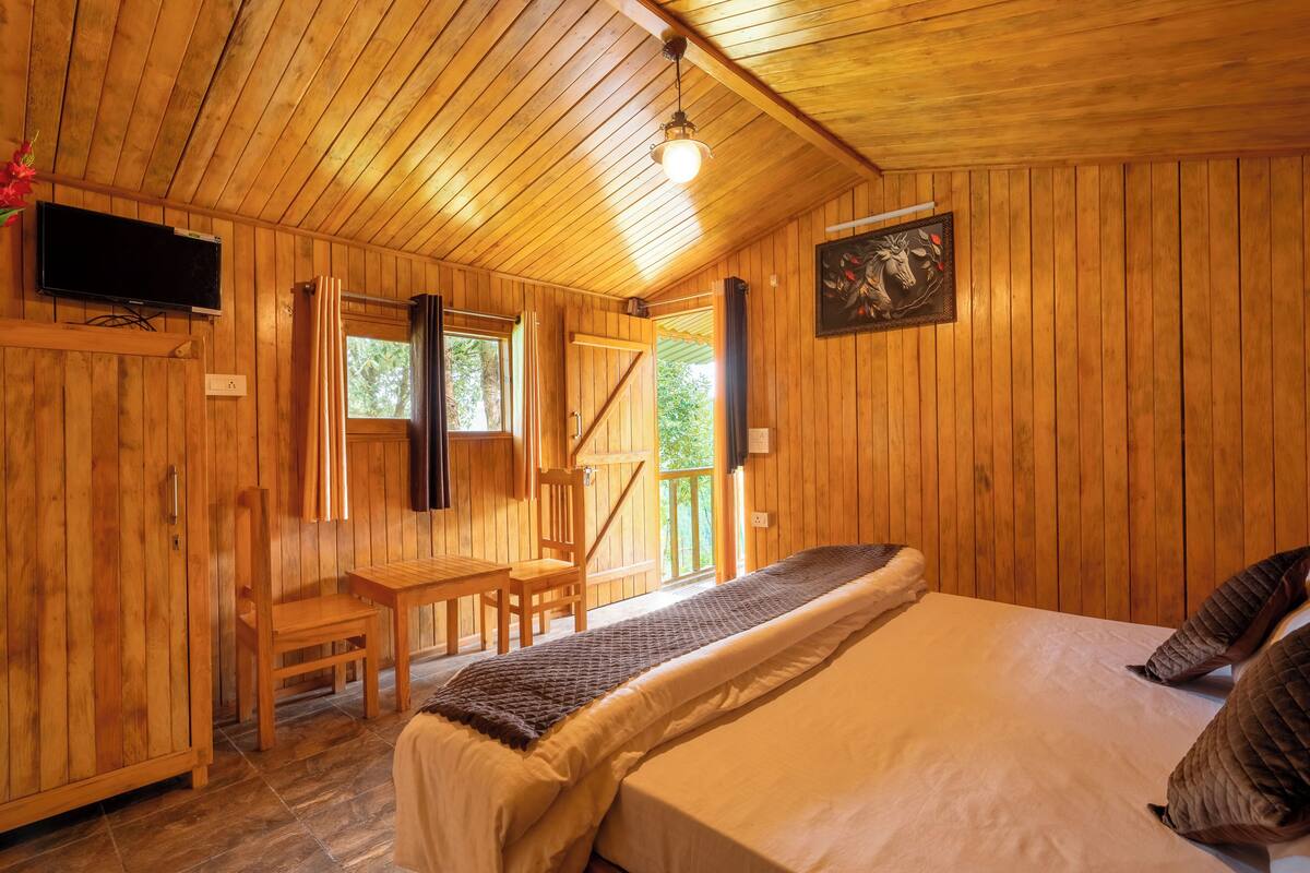 Ein Zimmer in einer Holzhütte mit einem Bett, einem Schreibtisch und einem Stuhl.