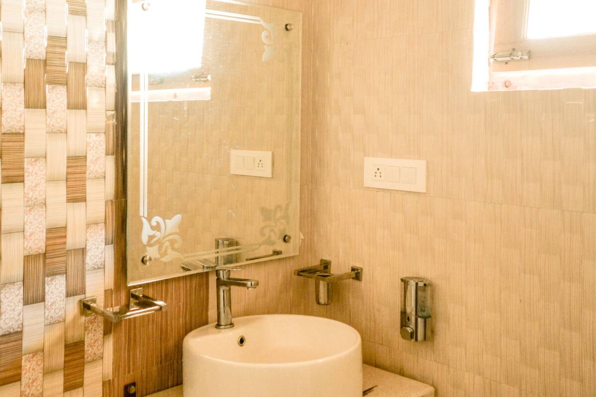 Ein Badezimmer mit einem runden Waschbecken, einem Spiegel und einem Fenster.