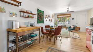 Une cuisine moderne avec des meubles en bois, un coin repas avec des chaises rouges et un salon avec un canapé turquoise.