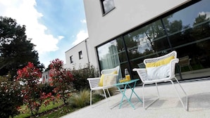 A modern building with large windows, white outdoor furniture, and a garden with red flowers. - Villa 6 persons golf de la Palmyre, special offers for riders (Les Mathes)