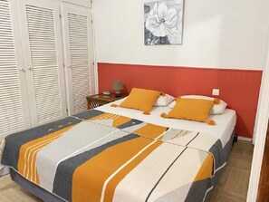 Quarto com cama, mesa de cabeceira, luminária e uma obra de arte na parede.