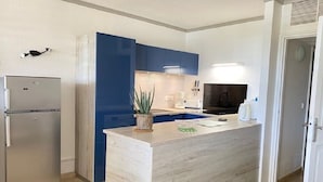 A modern kitchen with a central island, a built-in oven, and a refrigerator.
