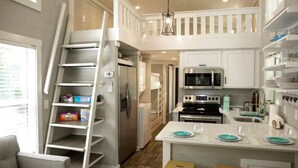 A modern kitchen with white cabinetry, stainless steel appliances, and a central island with stools. - Riverfront Home I Kayak & Fishing I 6 mins Mentone (Mentone)