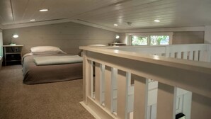 A bedroom with a bed, a nightstand, a window, and a white railing. - Riverfront Home I Kayak & Fishing I 6 mins Mentone (Mentone)