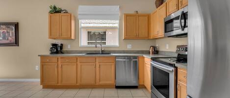 A modern kitchen with wooden cabinets, stainless steel appliances, and a dishwasher.