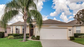A residential house with a garage, a well-maintained lawn, and a palm tree. - Stunning Villa with Ultimate Games Room (Haines City)