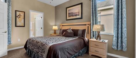 A bedroom with a bed, bedside table, lamp, and a ceiling fan.