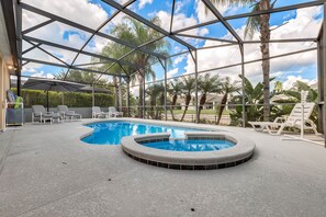 Piscina techada al aire libre con sillas de descanso y sombrillas, rodeada de palmeras y un cielo despejado.