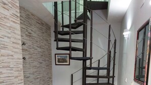 A modern interior with a spiral staircase, a glass table with a bench, and a framed picture on the wall. - navas suite (Navas del Rey)