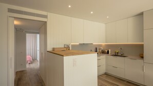 A modern kitchen with white cabinetry, a wooden countertop, and a built-in oven. - X-3 Ground floor apartment in community with pool (Calella de Palafrugell)