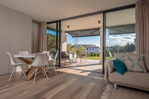 Una sala de estar moderna con comedor, puertas correderas de vidrio que dan a un patio, y un sofá con un cojín decorativo.