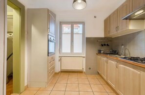 A kitchen with a window, cabinets, a stove, and a radiator.