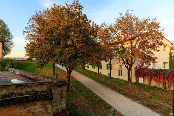 A pathway lined with trees and a building with green shutters. - CASA KATHY: Smart and Convenient Luxury 2 Bedrooms Apartment inside the City Walls (Lucca)