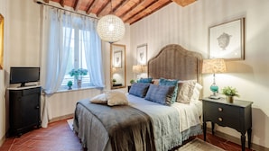 Un dormitorio con cama, televisión, candelabro y obras de arte en las paredes.