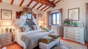 A bedroom with a four-poster bed, a white dresser, and a chandelier.