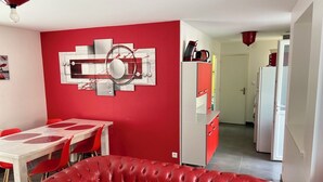 Un salon moderne avec un canapé rouge, une table à manger avec des chaises rouges et un meuble rouge et blanc.