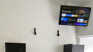 Une chambre avec un lit, un téléviseur fixé au mur et deux casiers métalliques noirs.