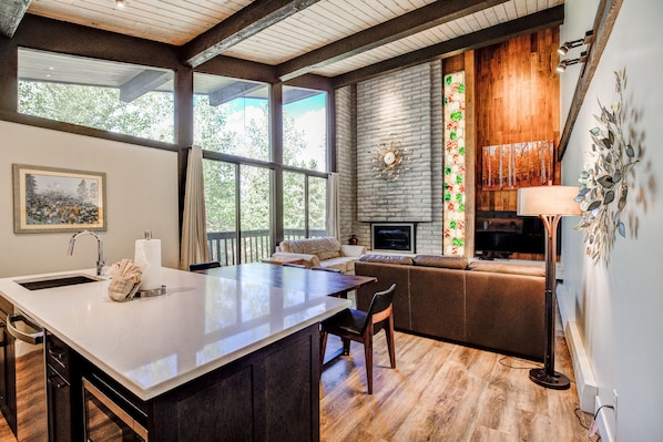 Une cuisine moderne dotée d’un grand îlot central, de planchers en bois et d’une cheminée en pierre.