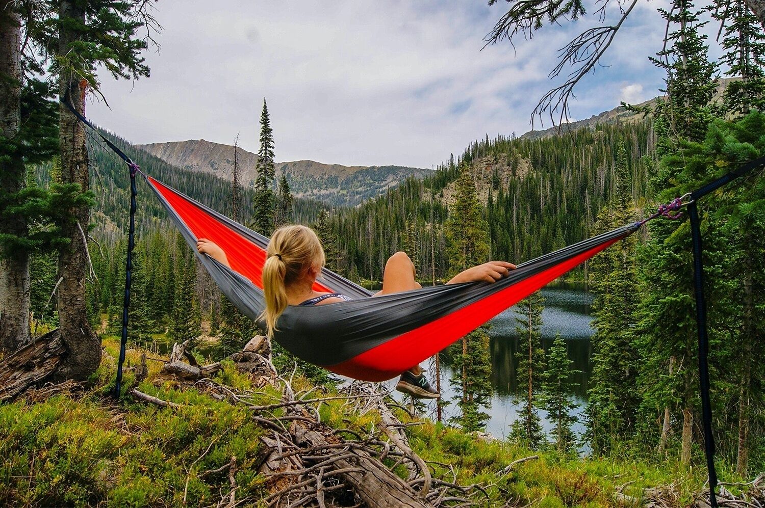 A person relaxing in a hammock with a mountain view.