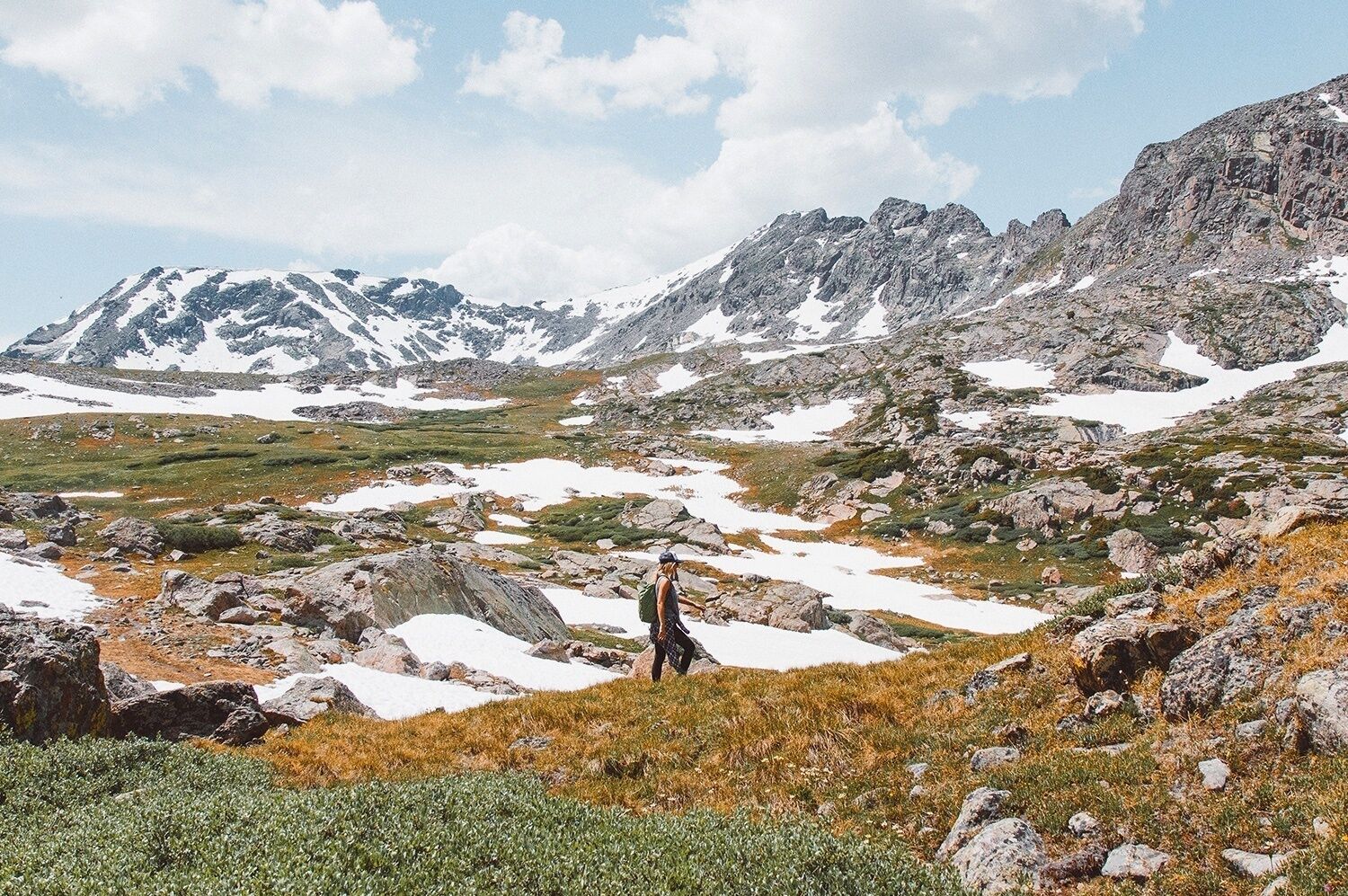 Eine Berglandschaft mit einer Person, die auf einem Felsen steht.