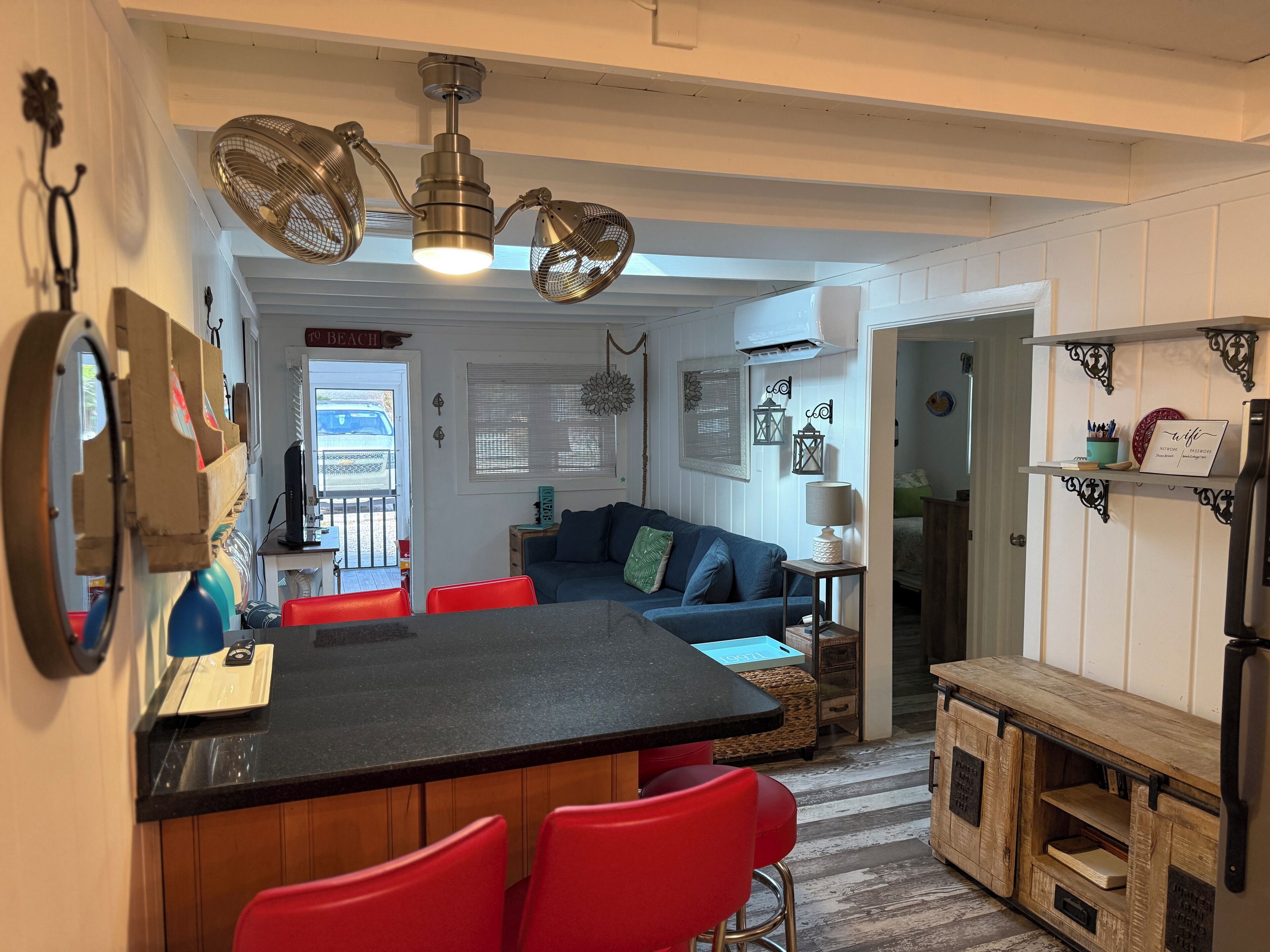 Una cocina compacta con una isla central, taburetes rojos y una mesa de comedor.