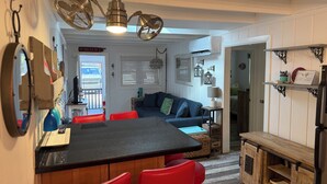 Una cocina compacta con una isla central, taburetes rojos y una mesa de comedor.