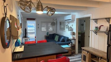 Una cocina compacta con una isla central, taburetes rojos y una mesa de comedor.