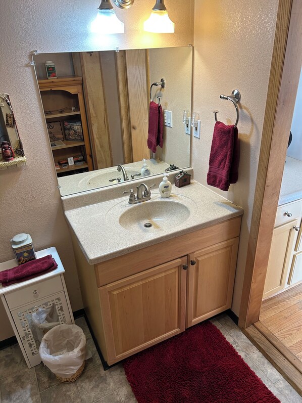 A bathroom with a sink, mirror, towel rack, and wooden cabinets.