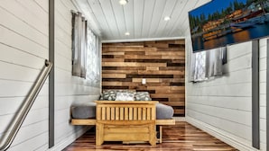 Un couloir étroit avec un banc en bois et un mur en bois orné d’un motif en chevrons.