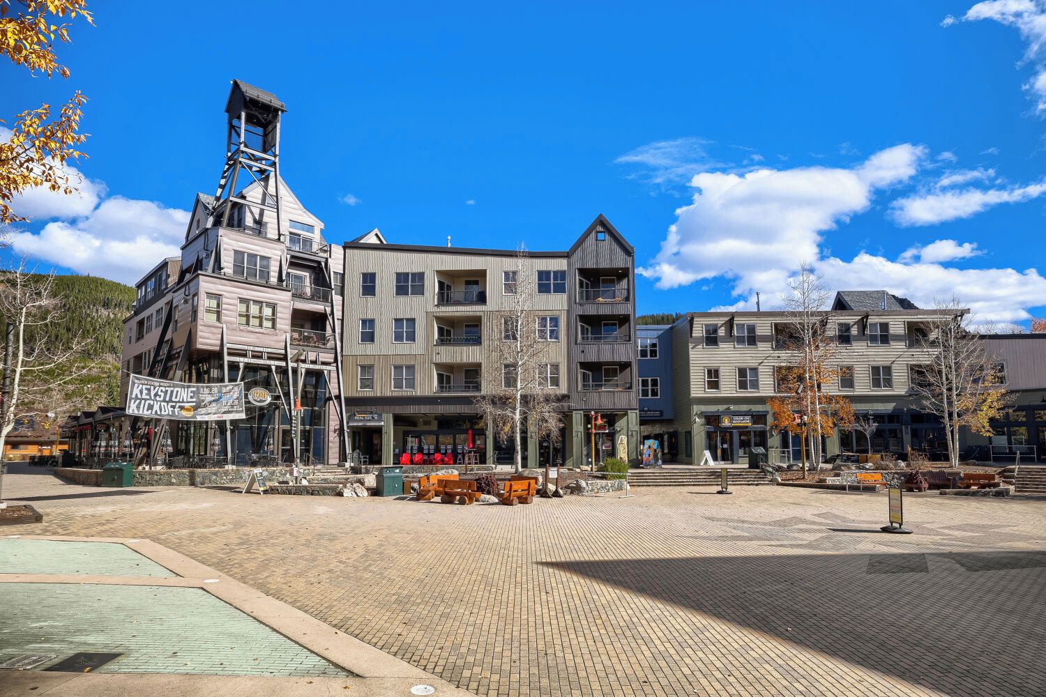 A multi-story building with a prominent tower, a paved plaza, and various storefronts.