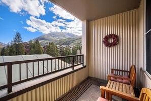 Un balcon avec vue sur les montagnes, une chaise en bois et une guirlande accrochée au mur.