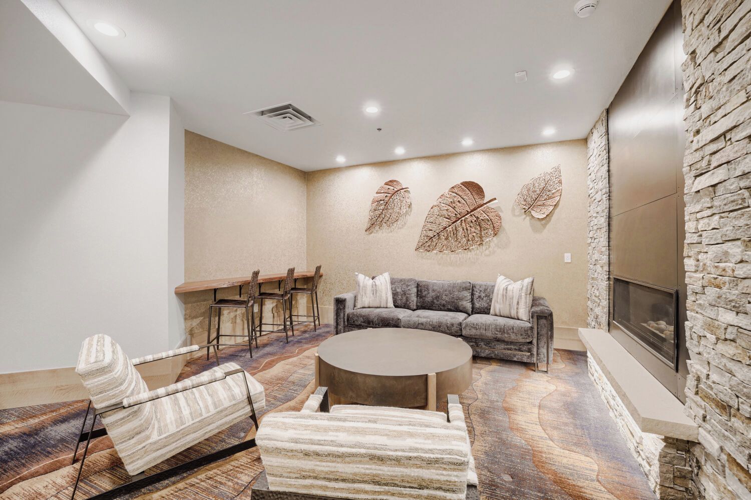 A modern living room with a sofa, chairs, a coffee table, and a fireplace.
