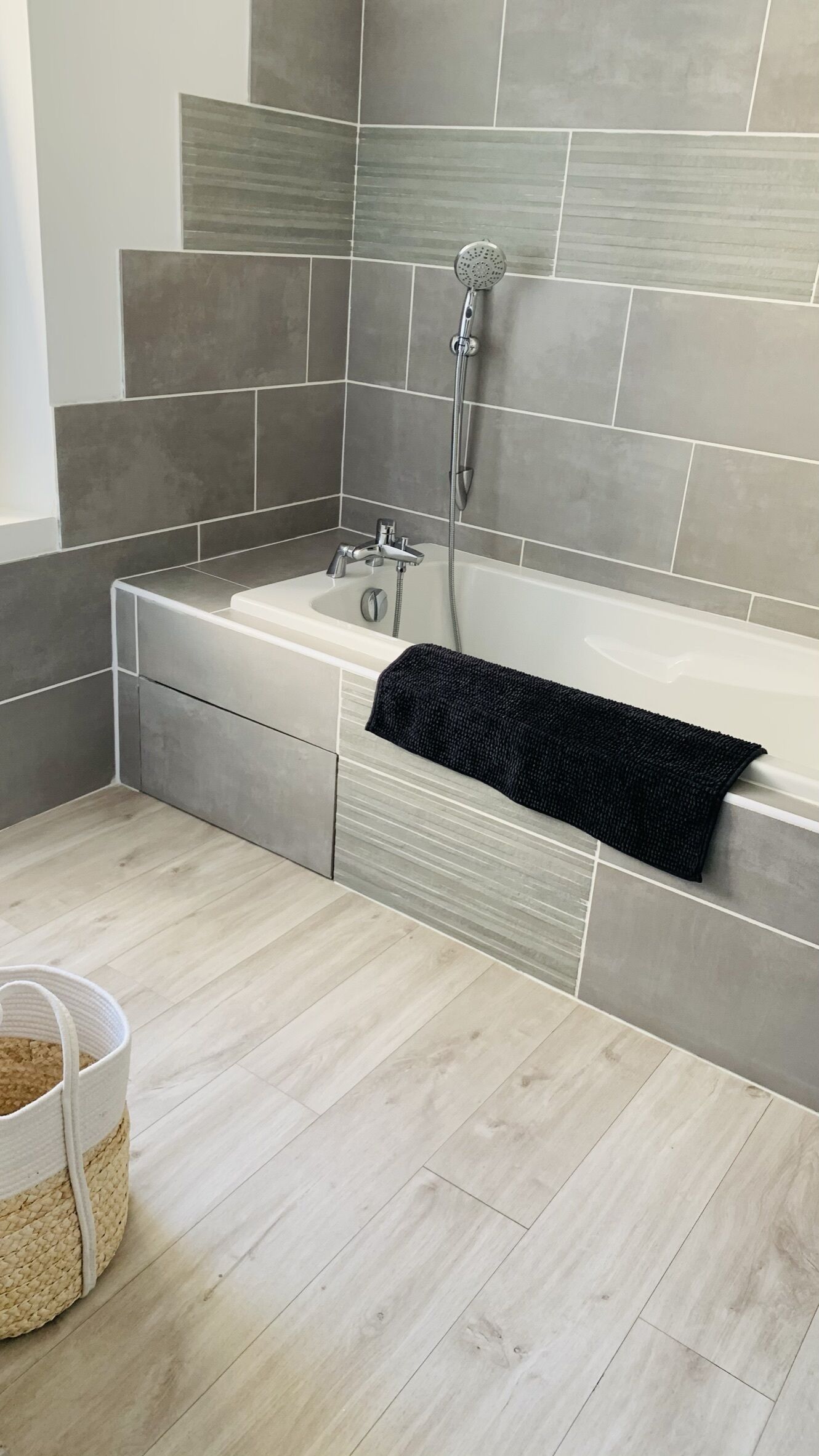Une salle de bain moderne avec une baignoire, une douche et des murs recouverts de carreaux gris.